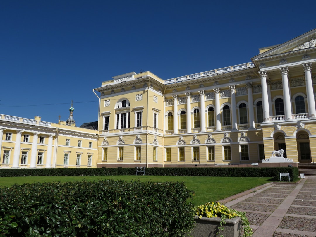a large yellow building with many windows and a lawn in front of it